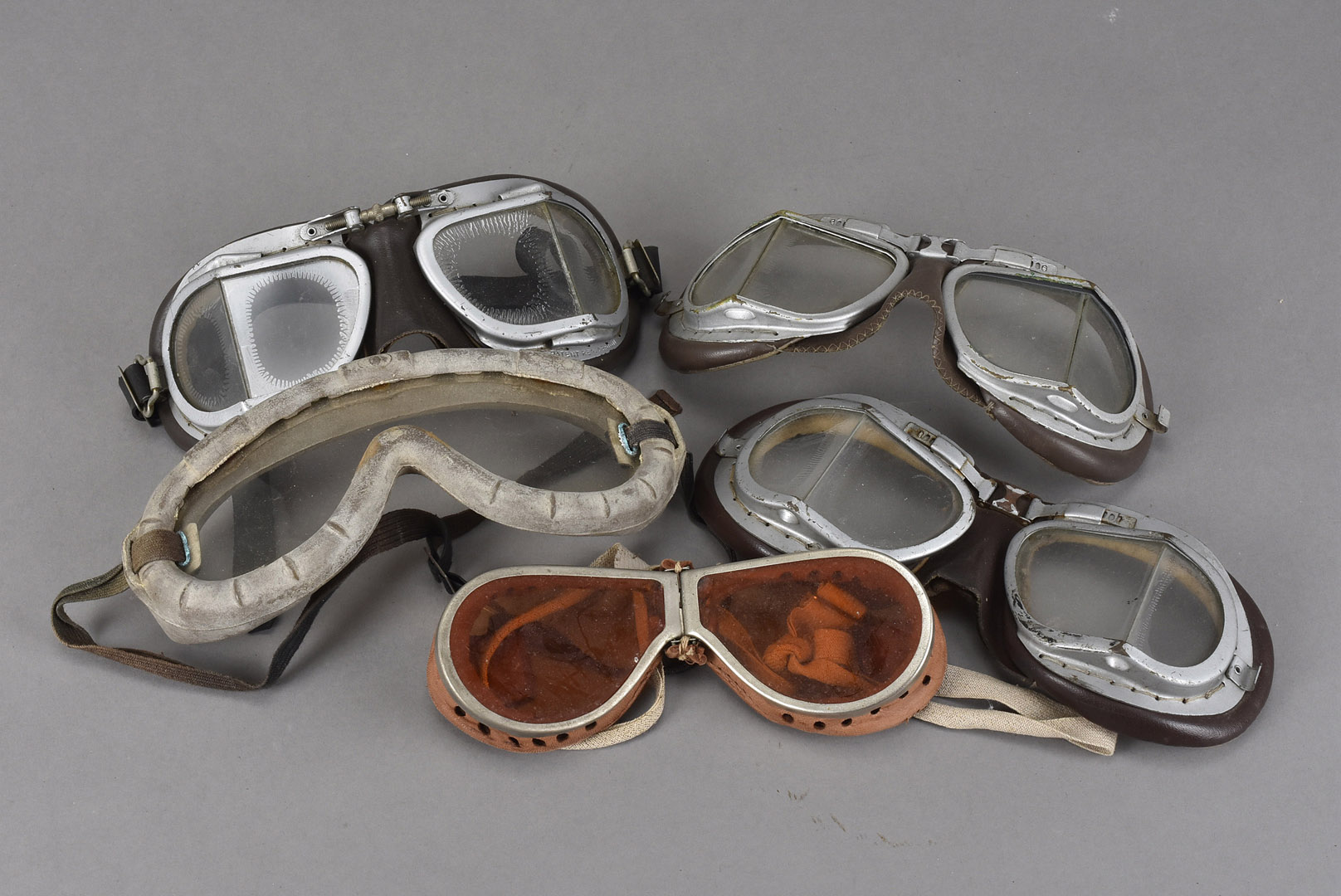 Five pairs of aviation/motoring goggles, three pairs are very similar, one pair with tinted orange