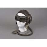 A WWII period brown leather flying helmet, unmarked, together with a pair of tinted flying goggles