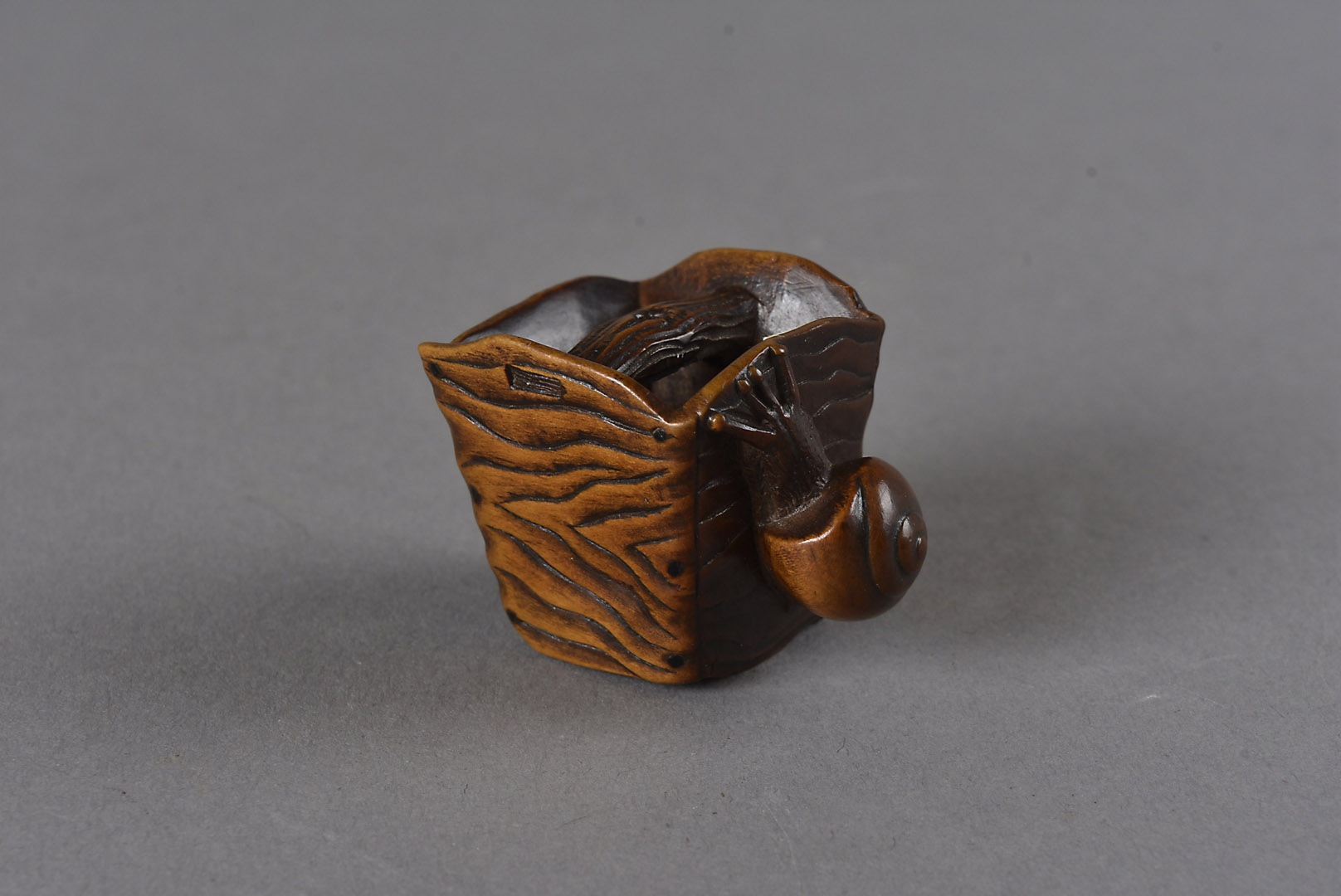 A Meiji period Japanese signed carved wood netsuke, modelled as a gong with large snail to one