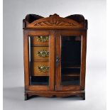 An Edwardian oak smokers bow cabinet with glazed panel doors, to fitted interior with three