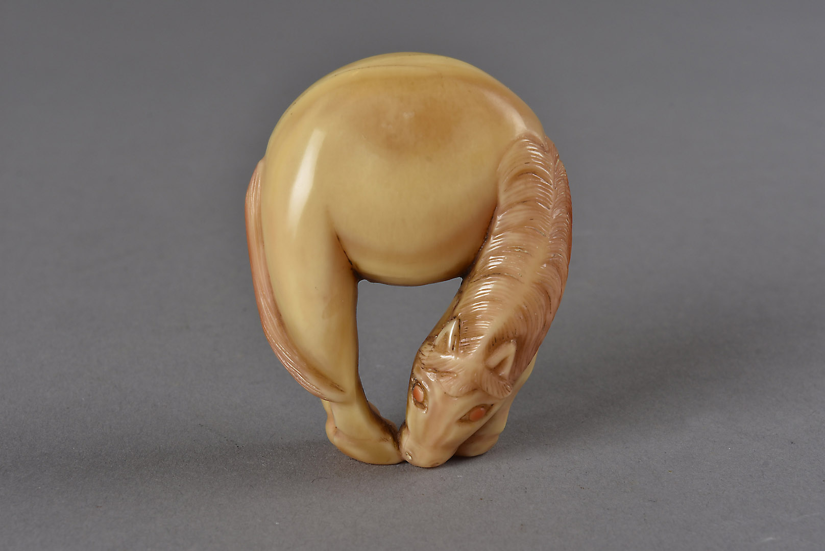 An early 19th Century Japanese Hornbill carved signed netsuke, modelled as a grazing horse, the