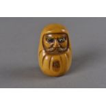 A signed Meiji period Japanese ivory netsuke, modelled as a durama with protruding eyes, and
