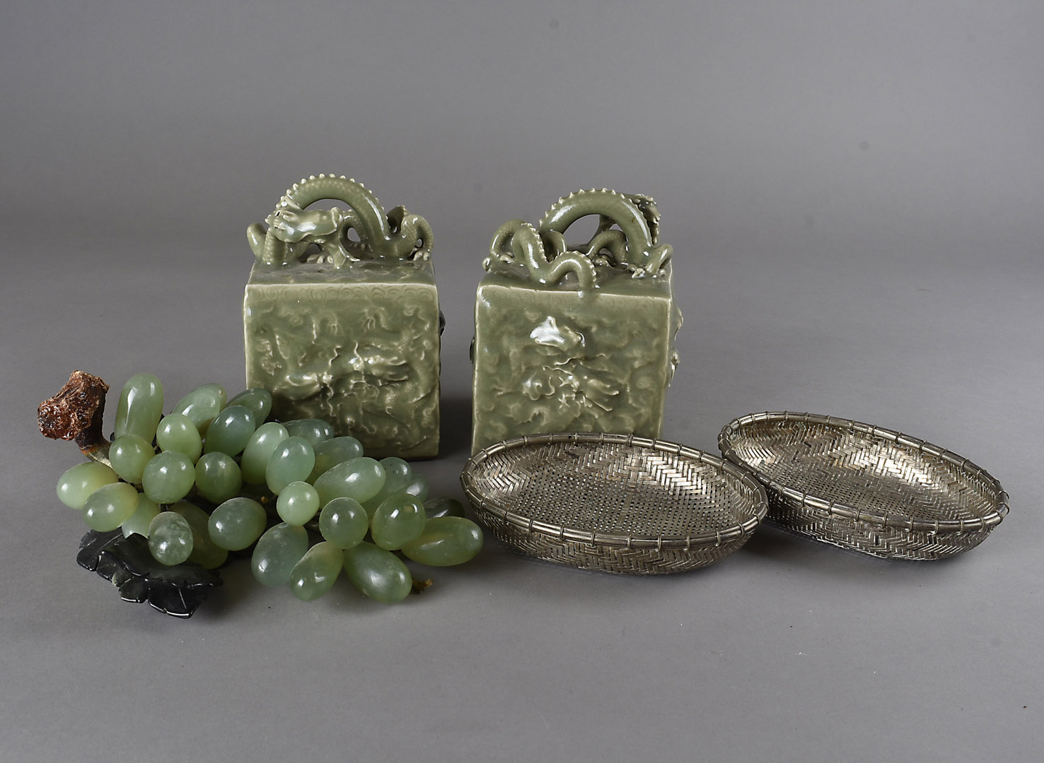 A pair of Chinese celadon glazed scroll weights, with seal marks to underside, decorated with