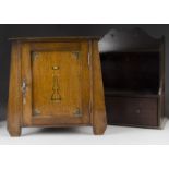 An Arts and Crafts oak smokers bow cabinet, of tapered shape, with stylised floral design to panel
