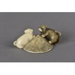 A Meiji period Japanese ivory netsuke, modelled as a pair of puppies playing on a coolie hat, one in