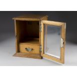 An Edwardian oak smokers cabinet, of rectangular shape, with glazed panel door, moulded top and