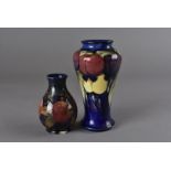 A Moorcroft pottery baluster vase, tube line decorated with plum and leaf design against a blue