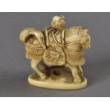A Japanese ivory netsuke, modelled as a horse and groom with an ornate decorative saddle and