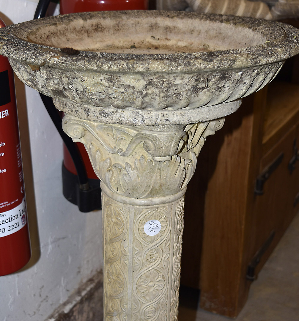 A reconstituted stone pedestal bird bath, the circular top supported on a moulded pedestal base