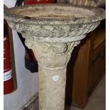 A reconstituted stone pedestal bird bath, the circular top supported on a moulded pedestal base