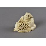 A signed 18th Century Japanese ivory netsuke, modelled as a seated man with a rat trap, signed to