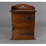 An Arts and Crafts oak smokers cabinet, the panel door with embossed metal straps and key escutcheon