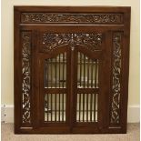 A hardwood mirror, the modern floral carved surround with a pair of arched lattice panel doors
