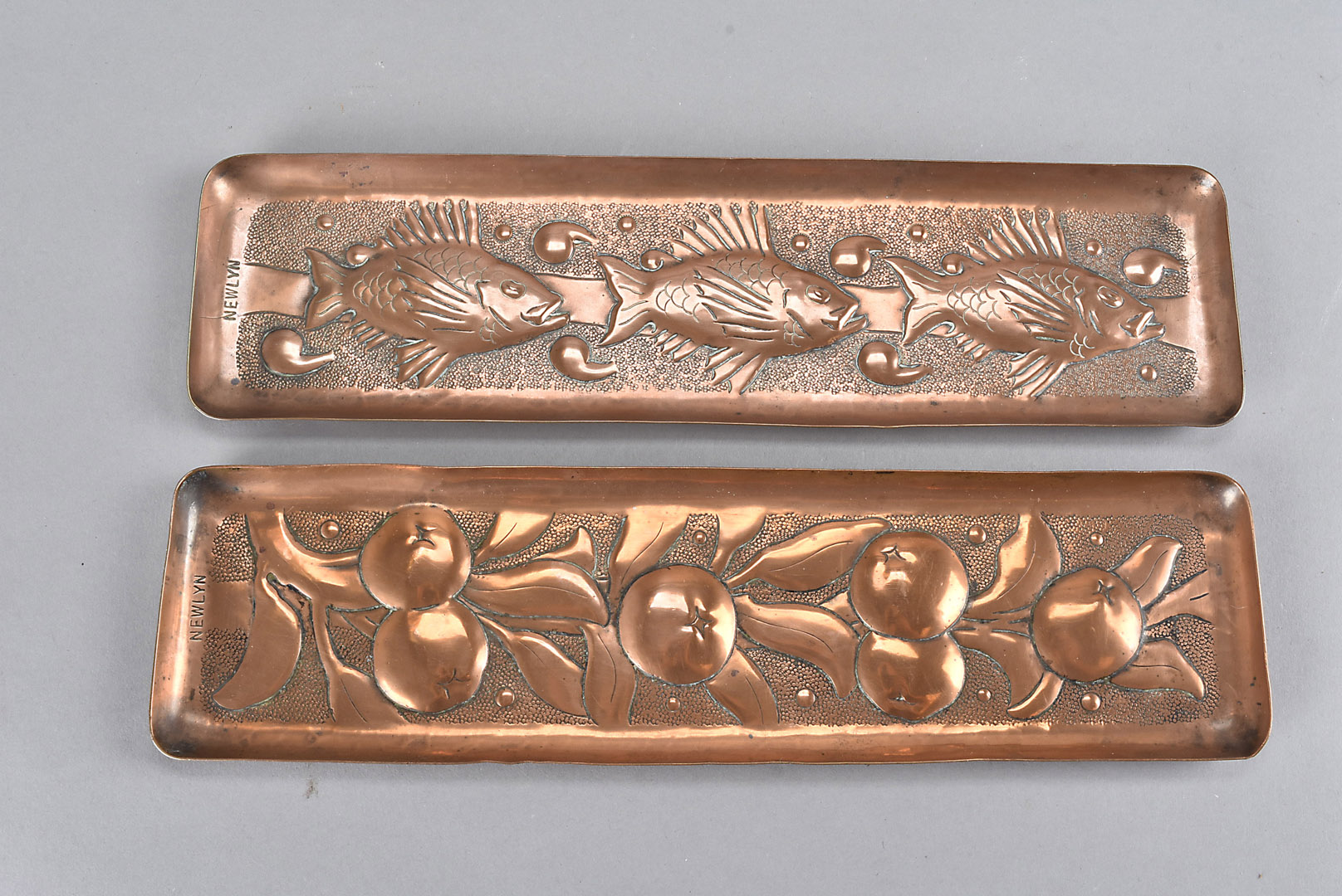 Two Newlyn arts and crafts copper rectangular trays, one embossed with three fish swimming amongst