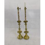 A pair of gothic revival brass ecclesiastical candlesticks, the tapered bases with crenulated sconce