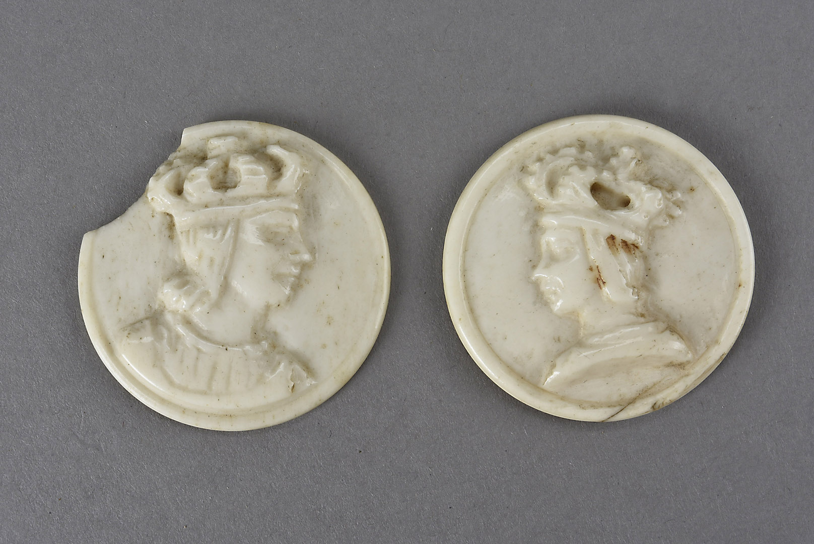 A pair of carved bone tokens, or decorative bosses, depicting a king and queen, each 1½ in (38 mm)