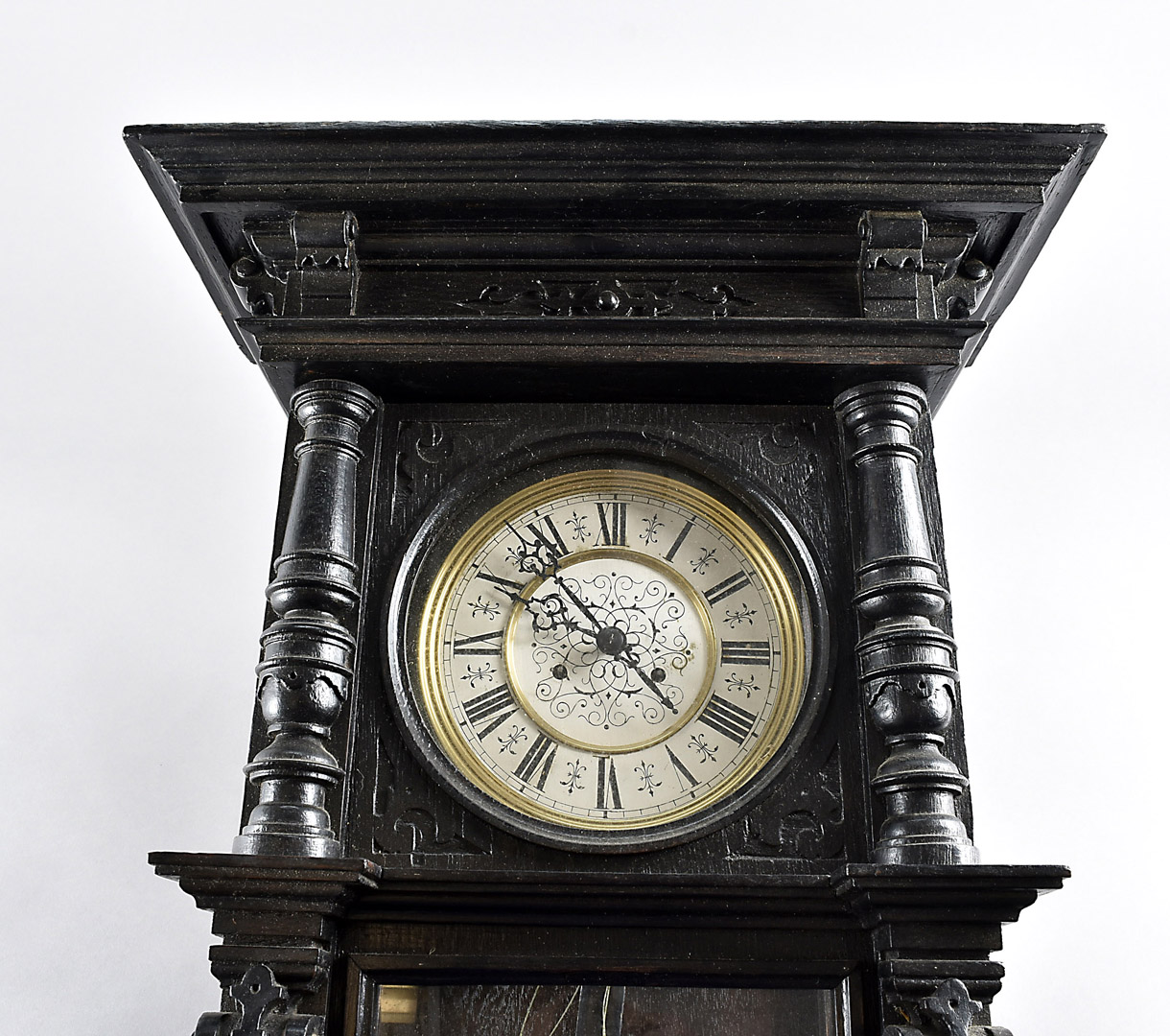 An Edwardian ebonised Vienna style wall clock, with eight day movement within an ornate carved