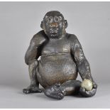 An early 20th Century plaster figure of a seated chimpanzee, with glass eyes, one hand holding a