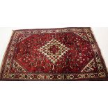 A red ground Hamadan Doz carpet, central medallion, in all over burgundy colours surrounded by