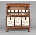 A continental stained beech and pottery spice rack, having floral decorated ceramic drawers and