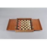 An Edwardian travelling mahogany, rosewood and satinwood chess set, the bone carved pieces, either
