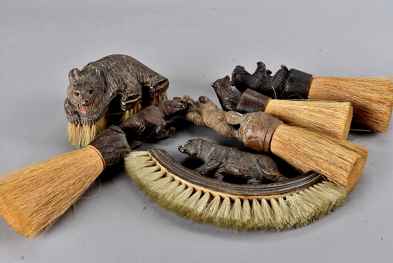 A collection of six Black Forest carved bear mounted table brushes, largest 19 cm (6)