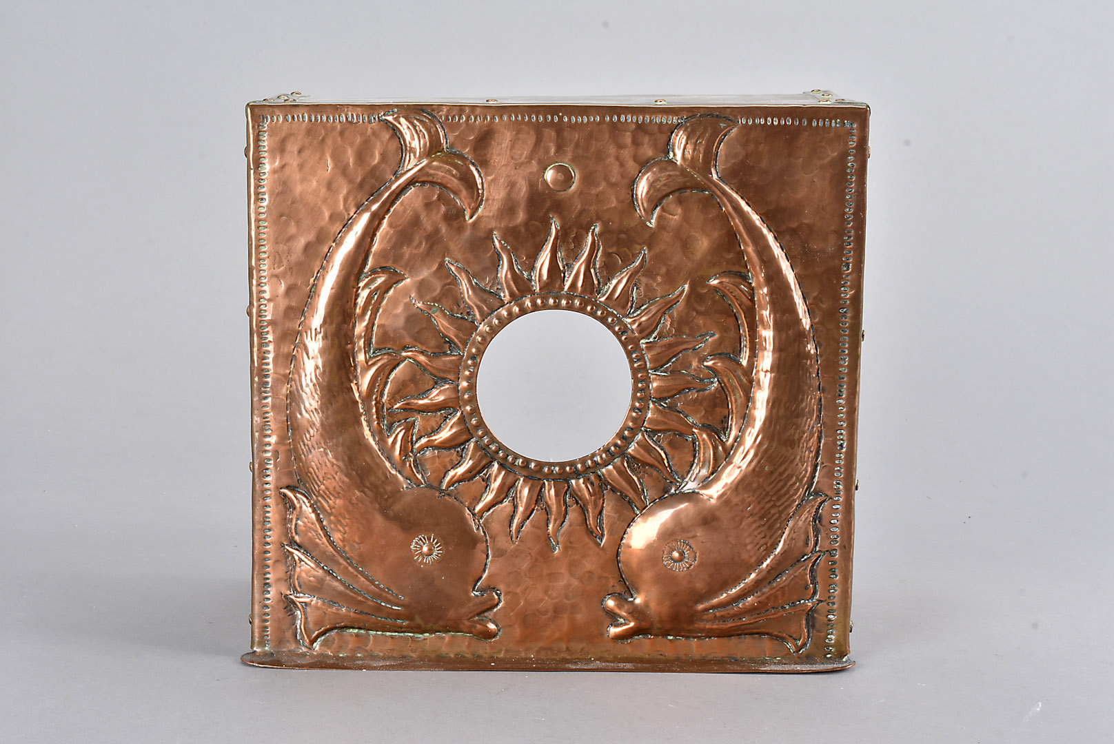 An arts and crafts copper watch stand, with hammer beaten decoration of stylised dolphins