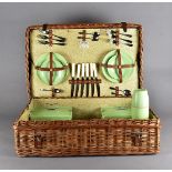 A Harrods Coracle picnic basket, the wicker basket with green plastic containers, plates, knives and
