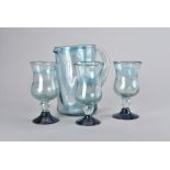 A studio soda glass lemonade set, comprising jug and six stemmed goblets with blue spreading feet (