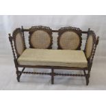 A Carolean style high backed settee, with carved top rails, oval caned back panels supported on