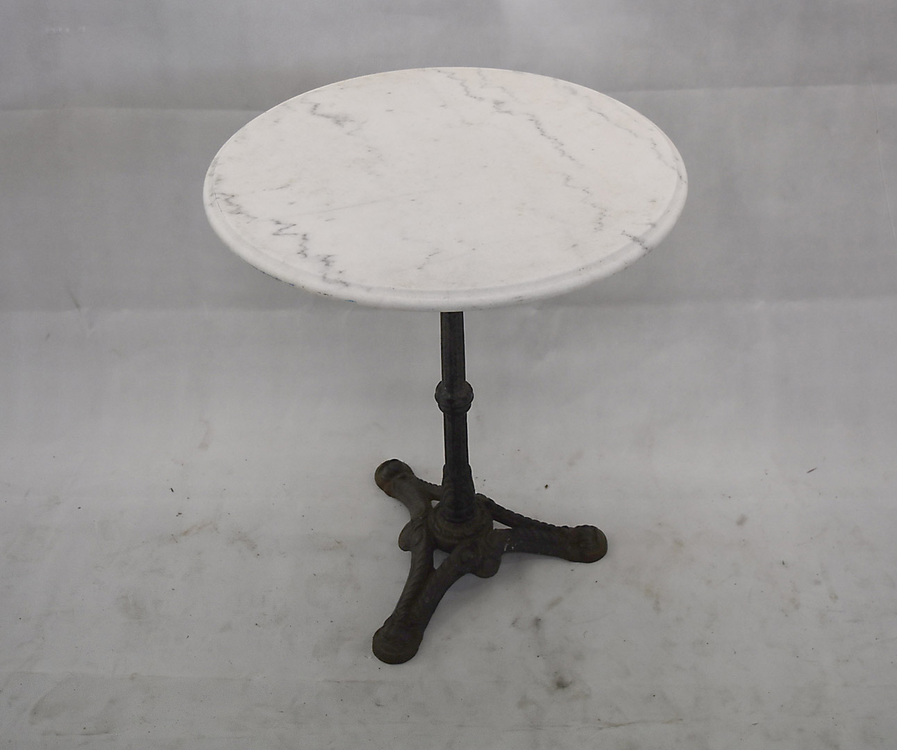 A cast iron and marble topped garden table, circular top, 60 cm diameter x 72 cm high