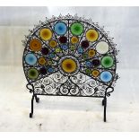 A peacock wrought iron and coloured glass fire screen, 84 cm high x 77 cm max