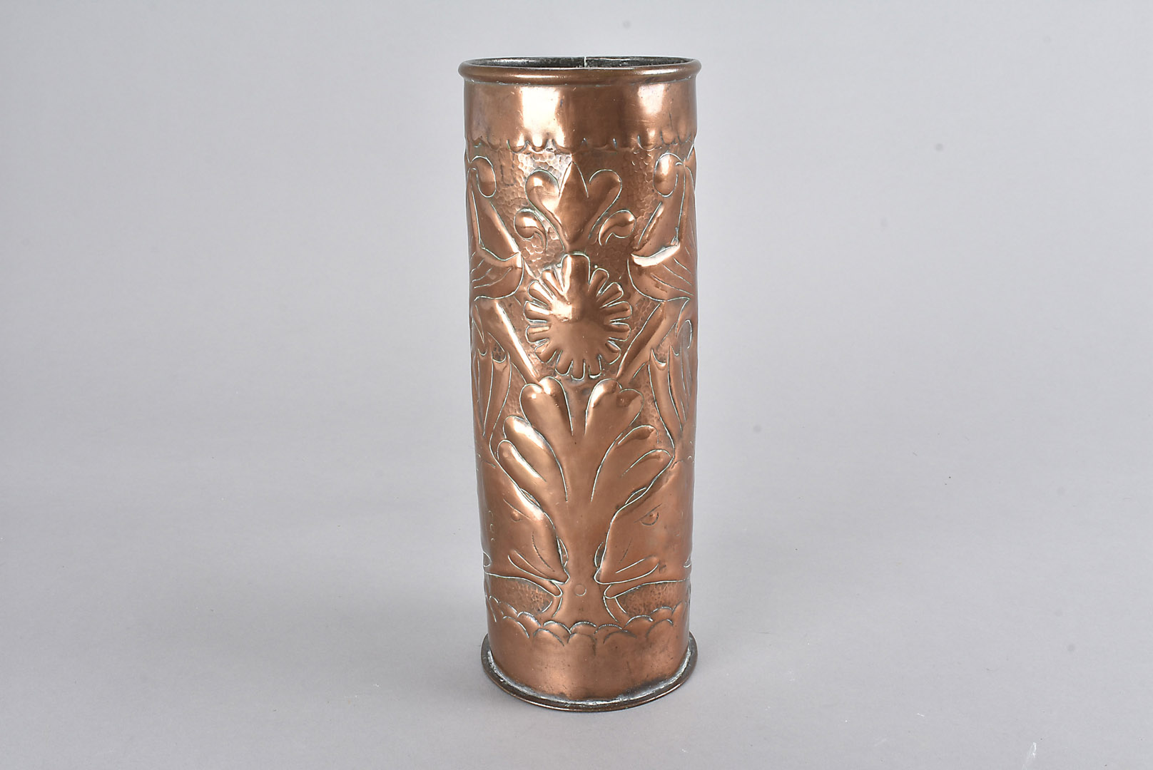 An arts and crafts copper sleeve vase, decorated with feeding fish with central seaweed and shell