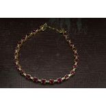 A modern 18ct gold ruby and diamond line bracelet, having links set alternately with oval rubies and