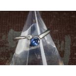 A modern platinum diamond and sapphire ring, with pear shaped blue sapphire and a brilliant cut in