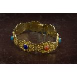 A 1980s Middle Eastern gold and semi precious stone bracelet, having seven shaped panels set with