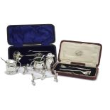 A George V silver three piece cruet set by L & S, with two spoons, together with a pair of silver