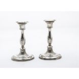 A pair of late Victiorian silver candlesticks, possibly by the Hennells, filled, with leaf design to
