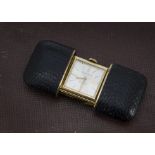 An Art Deco purse watch, the black snake or lizard skin case sliding open to reveal gilt clock
