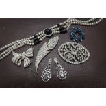 A collection of paste and costume jewellery, including a leaf brooch, a bow brooch, and more (