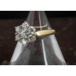 A modern diamond flower head cluster ring, having seven brilliant cuts in an 18ct gold mount, 4.7g