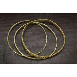 A group of three Middle Eastern yellow metal bangles, of differing patterns, 29g, 6.5cm and 7cm