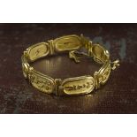 A 1970s Eygptian gold bracelet, having seven oblong panels with hyrogliphs, stamped to clasp, 39.4g,