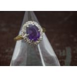 A 1970s 18ct gold and amethyst cluster dress ring, oval purple stone surrounded by brilliant cuts,