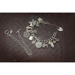 A silver charm bracelet, curb link chain supporting multiple charms, together with a silver bracelet