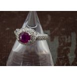 A modern 18ct gold and ruby dress ring, the oval red stone in white gold mount encrusted with