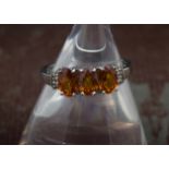 A modern 9ct white gold three stone orange garnet ring, oval probably spessartite stones