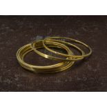 A collection of ten Indian or Far Eastern yellow metal bangles, plain outers, some with stamped