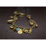 A vintage gold and yellow metal charm bracelet, oval link chain supporting multiple charms such as a