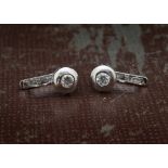 A modern pair of 18ct white gold and diamond earrings, rubbed over lowers set with a brilliant cut